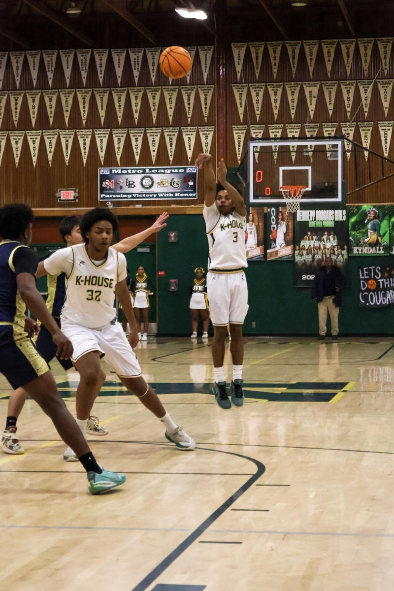On February 11 in the Kennedy gym, Marcus Menefee takes a three point shot while a defender rushes to guard him.
